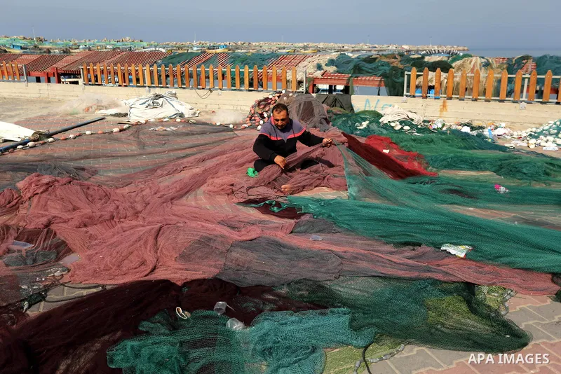 A Palestinian fisherman fixes his fishing nets during a ceremony of support Palestinian fishermen project funded by the national islamic committee for development and social solidarity, in Gaza sea port on February 3, 20...