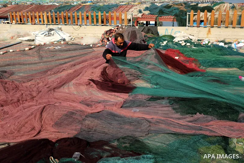 A Palestinian fisherman fixes his fishing nets during a ceremony of support Palestinian fishermen project funded by the national islamic committee for development and social solidarity, in Gaza sea port on February 3, 20...