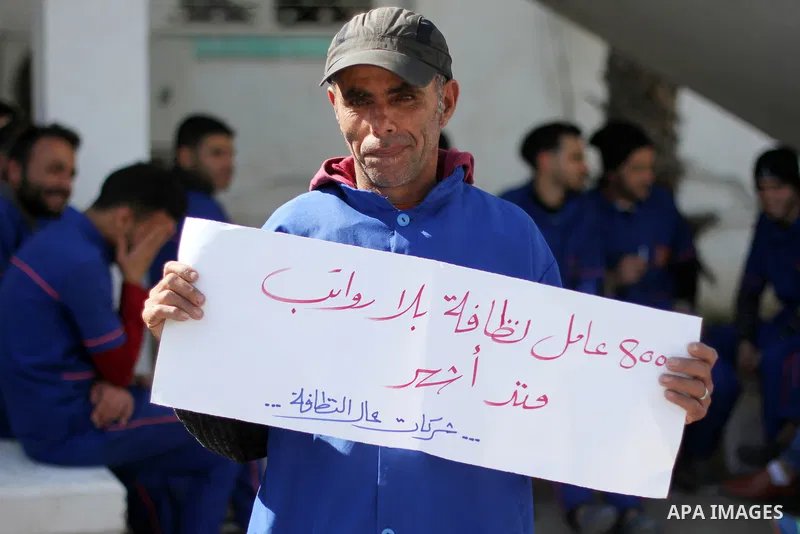 Palestinian cleaners hold banners during a protest to demand their salaries, at al-Shifa hospital in Gaza City on February 4, 2018. Photo by Mahmoud Ajour