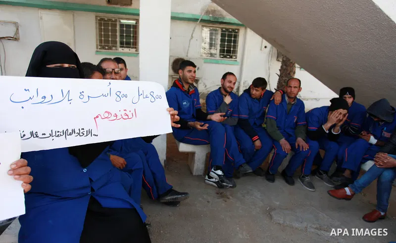 Palestinian cleaners hold banners during a protest to demand their salaries, at al-Shifa hospital in Gaza City on February 4, 2018. Photo by Mahmoud Ajour