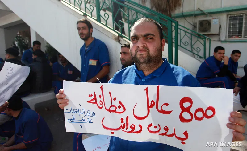 Palestinian cleaners hold banners during a protest to demand their salaries, at al-Shifa hospital in Gaza City on February 4, 2018. Photo by Mahmoud Ajour