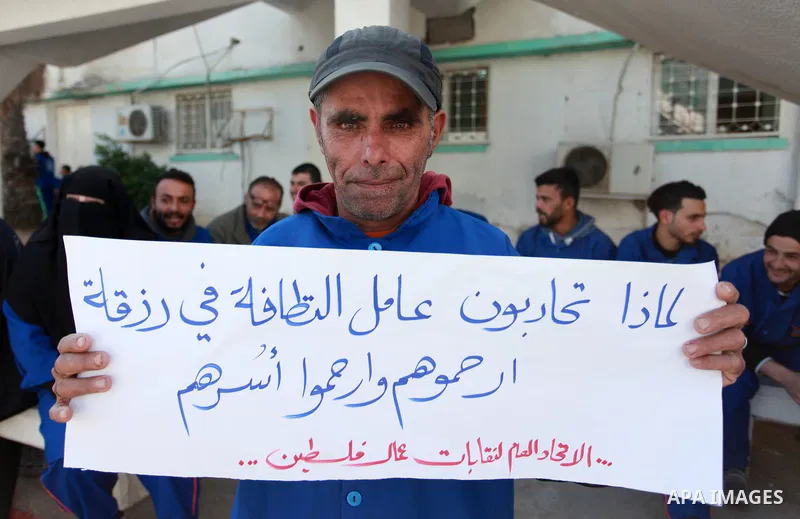 Palestinian cleaners hold banners during a protest to demand their salaries, at al-Shifa hospital in Gaza City on February 4, 2018. Photo by Mahmoud Ajour