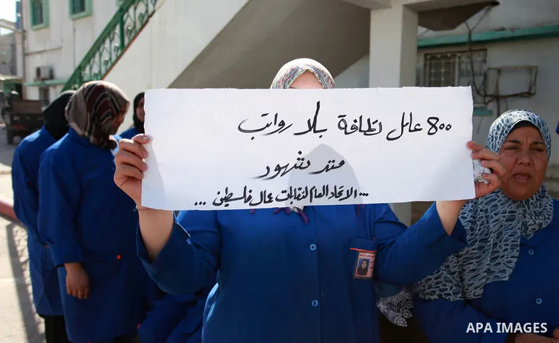 Palestinian cleaners hold banners during a protest to demand their salaries, at al-Shifa hospital in Gaza City on February 4, 2018. Photo by Mahmoud Ajour