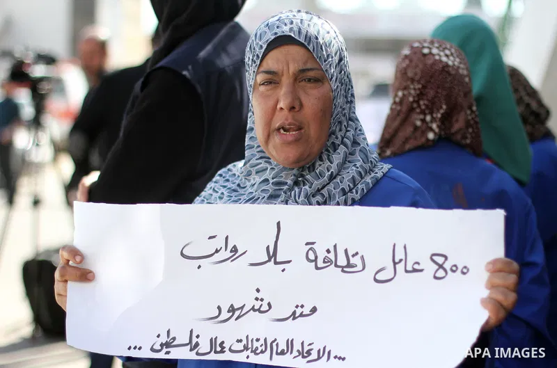 Palestinian cleaners hold banners during a protest to demand their salaries, at al-Shifa hospital in Gaza City on February 4, 2018. Photo by Mahmoud Ajour