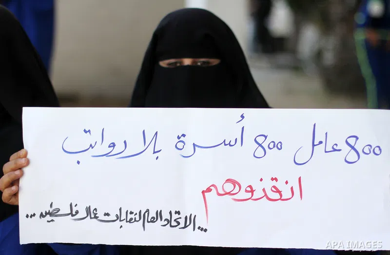 Palestinian cleaners hold banners during a protest to demand their salaries, at al-Shifa hospital in Gaza City on February 4, 2018. Photo by Mahmoud Ajour