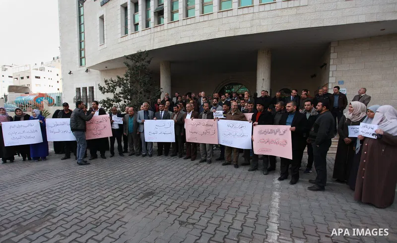 Palestinian employees of the Ministry of Education hold banners during a protest against the US move to freeze funding for the UN agency for Palestinian refugees, in Gaza city, on February 5, 2018. Photo by Mahmoud Ajour