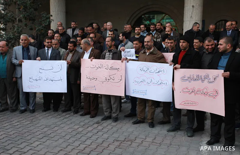 Palestinian employees of the Ministry of Education hold banners during a protest against the US move to freeze funding for the UN agency for Palestinian refugees, in Gaza city, on February 5, 2018. Photo by Mahmoud Ajour