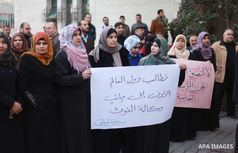 Palestinian employees of the Ministry of Education hold banners during a protest against the US move to freeze funding for the UN agency for Palestinian refugees, in Gaza city, on February 5, 2018. Photo by Mahmoud Ajour