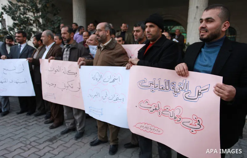 Palestinian employees of the Ministry of Education hold banners during a protest against the US move to freeze funding for the UN agency for Palestinian refugees, in Gaza city, on February 5, 2018. Photo by Mahmoud Ajour