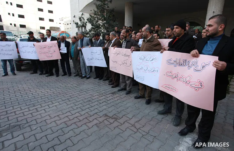Palestinian employees of the Ministry of Education hold banners during a protest against the US move to freeze funding for the UN agency for Palestinian refugees, in Gaza city, on February 5, 2018. Photo by Mahmoud Ajour