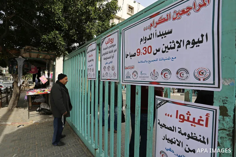 A Palestinian man stands in front of a closed entrance of Ministry of Health headquarter as Palestinian Ministry of Health employees take part during a protest demanding their rights and against deterioration of health c...