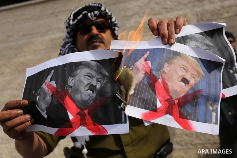 A Palestinian demonstrator burns posters of U.S. President Donald Trump during a protest to show solidarity with Palestinian prisoners held in Israeli jails, in front of Red cross office in Gaza city on February 5, 2018....