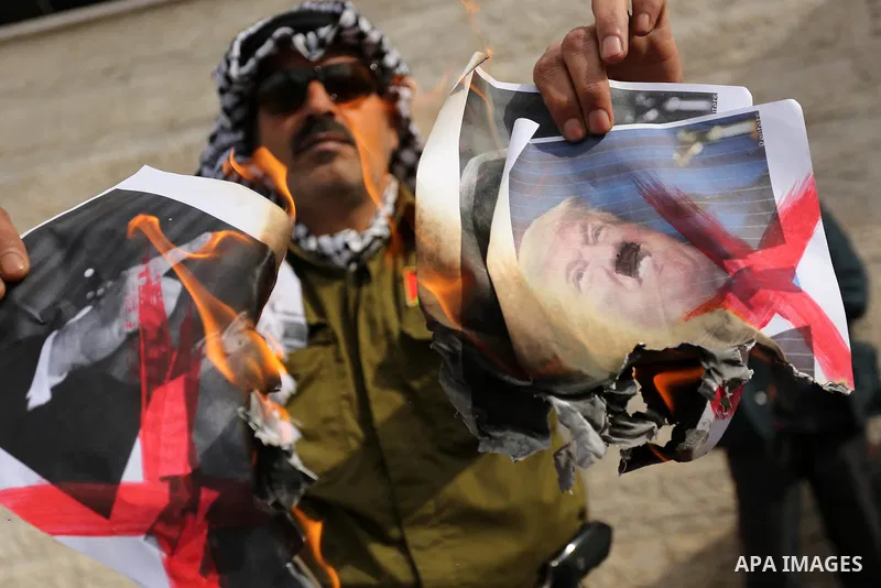 A Palestinian demonstrator burns posters of U.S. President Donald Trump during a protest to show solidarity with Palestinian prisoners held in Israeli jails, in front of Red cross office in Gaza city on February 5, 2018....