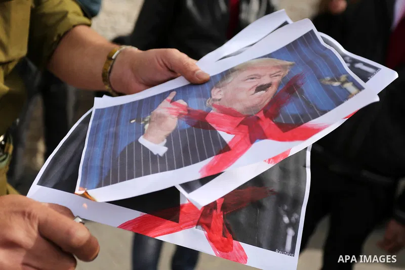 A Palestinian demonstrator burns posters of U.S. President Donald Trump during a protest to show solidarity with Palestinian prisoners held in Israeli jails, in front of Red cross office in Gaza city on February 5, 2018....