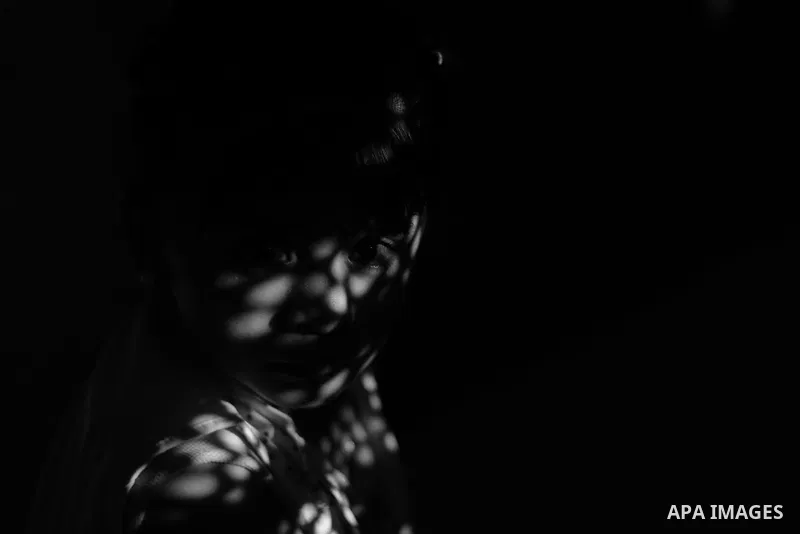 Close up of a little girl face illuminated through a window blind, Focus on the eye, High contrast, black and white. Photo by Sanad Ltefa