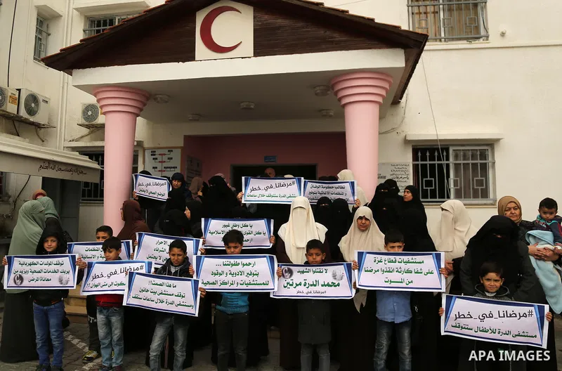 Palestinians hold placards during a protest outside Durra hospital in Gaza City after it stopped its services on February 7, 2018 after it ran out of fuel. Seven medical centers in Gaza have stopped services due to lack...