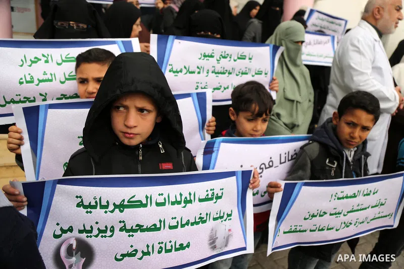 Palestinians hold placards during a protest outside Durra hospital in Gaza City after it stopped its services on February 7, 2018 after it ran out of fuel. Seven medical centers in Gaza have stopped services due to lack...