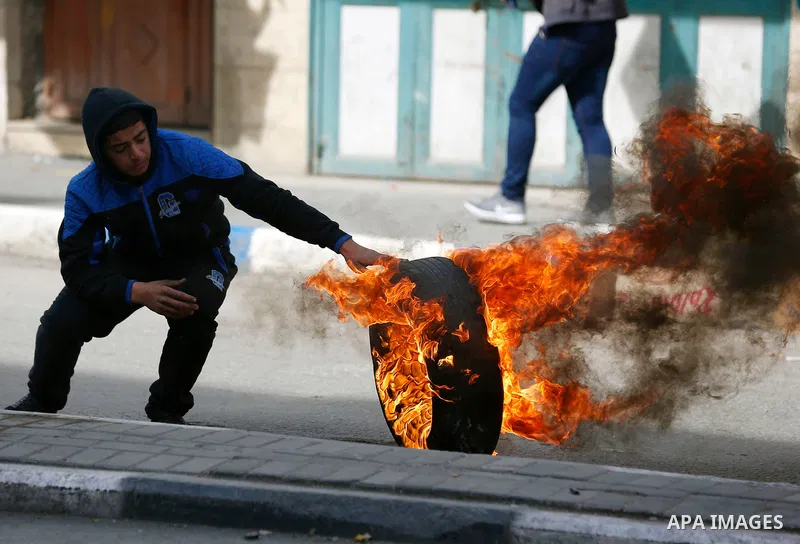 A Palestinian protester burns tires during clashes with Israeli security forces as demonstrations continue over US President Donald Trump's declaration of Jerusalem as Israel's capital, in the West Bank city of Hebron on...