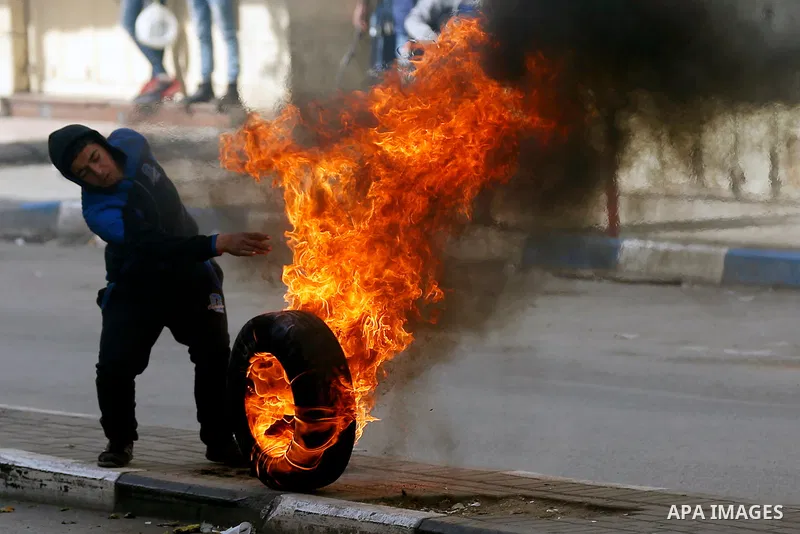 A Palestinian protester burns tires during clashes with Israeli security forces as demonstrations continue over US President Donald Trump's declaration of Jerusalem as Israel's capital, in the West Bank city of Hebron on...