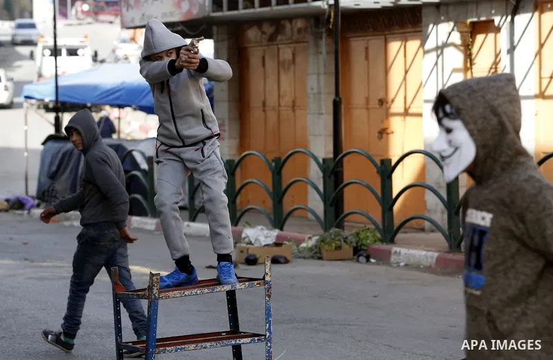 A Palestinian youth brandishes a plastic cap gun during clashes with Israeli security forces as demonstrations continue over US President Donald Trump's declaration of Jerusalem as Israel's capital, in the West Bank city...