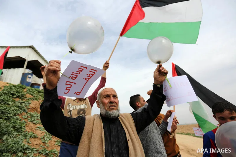 Palestinians hold national flags, placards and balloons during a protest title "Message from Gaza to West Bank" near the border with Israel, in Jabalia in the northern Gaza Strip on February 10, 2018. Photo by Ashraf Amr...