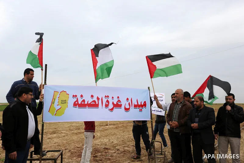 Palestinians hold national flags and placards during a protest title "Message from Gaza to West Bank" near the border with Israel, in Jabalia in the northern Gaza Strip on February 10, 2018. Photo by Ashraf Amra