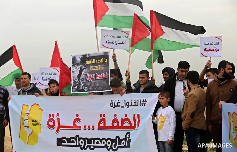 Palestinians hold national flags and placards during a protest title "Message from Gaza to West Bank" near the border with Israel, in Jabalia in the northern Gaza Strip on February 10, 2018. Photo by Ashraf Amra