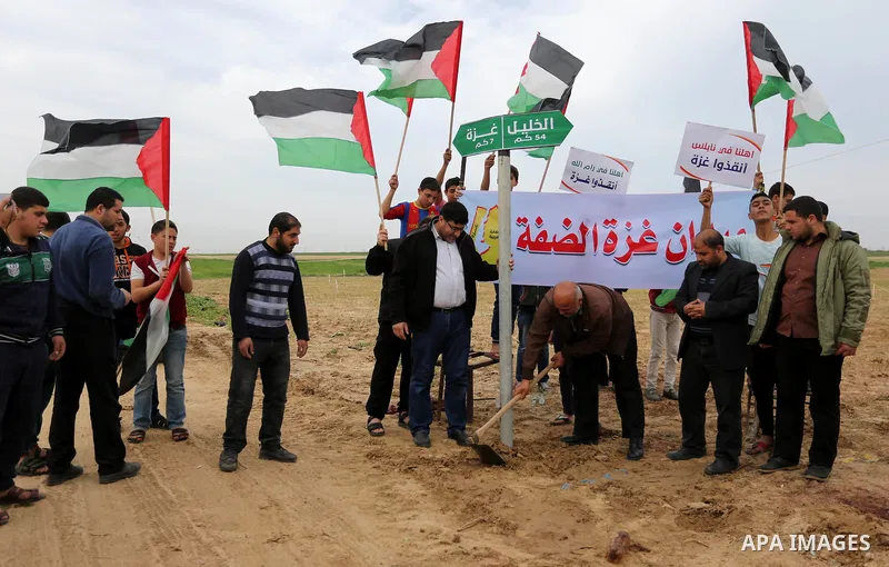 Palestinians hold national flags and placards during a protest title "Message from Gaza to West Bank" near the border with Israel, in Jabalia in the northern Gaza Strip on February 10, 2018. Photo by Ashraf Amra