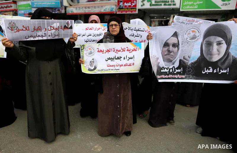 Palestinian women hold placards during a protest in solidarity with prisoner Esraa Al-Jabbais held in Israeli jails, at the al-Nusairat refugee camp, in central Gaza Strip, on February 10, 2018. Photo by Ashraf Amra