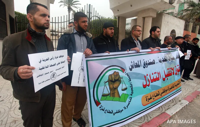 Palestinian employees of Gaza strip hold banners during a demonstration demanding their salaries, in front of the legislative council, in Gaza city, on February 11, 2018. Photo by Mahmoud Ajour