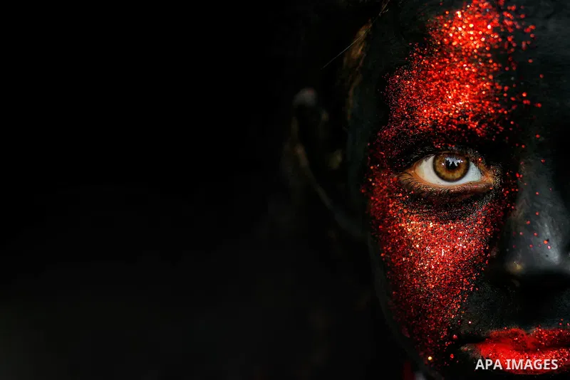 Cropped portrait of a girl with black red colored face. Photo by Sanad Ltefa