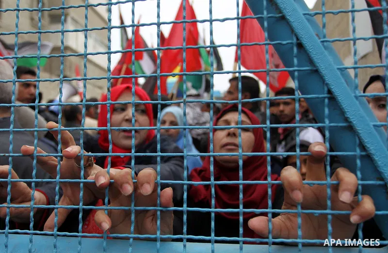 Palestinians shout slogans during a protest against US aid cuts, outside the United Nations' offices at the Khan Yunis refugee camp in the southern Gaza Strip on February 11, 2018. The writing in Arabic reads: "Yes, to n...