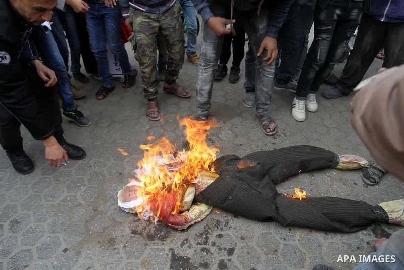 Palestinian demonstrators burn an effigy depicting U.S. President Donald Trump during a protest against US aid cuts, outside the United Nations' offices at the Khan Yunis refugee camp in the southern Gaza Strip on Februa...