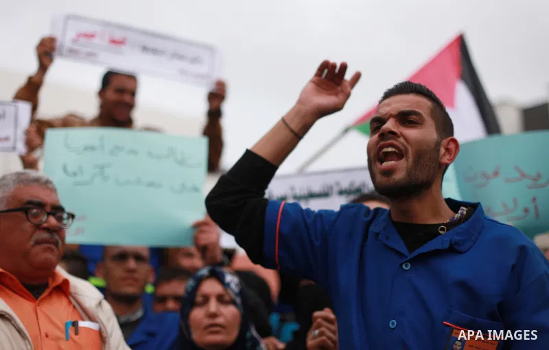 Palestinian cleaners hold banners during a protest to demand their salaries, at al-Shifa hospital in Gaza City on February 12, 2018. Photo by Mahmoud Ajour