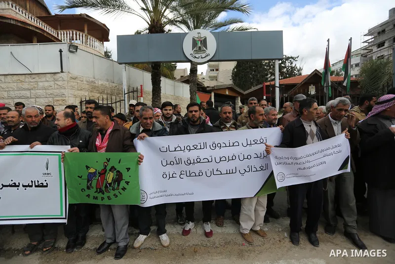 Palestinians hold banners during a solidarity with farmers affected by natural disasters, in front of the headquarters of the Council of Ministers in Gaza city on February 13, 2018. Photo by Ashraf Amra