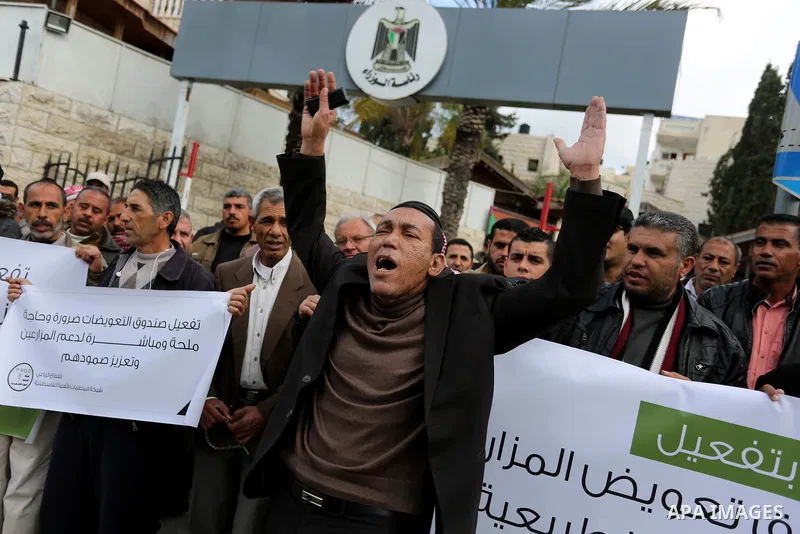 Palestinians hold banners during a solidarity with farmers affected by natural disasters, in front of the headquarters of the Council of Ministers in Gaza city on February 13, 2018. Photo by Ashraf Amra
