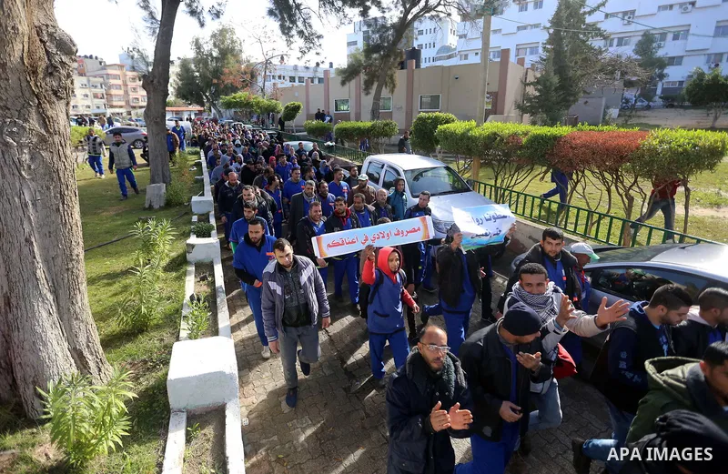 Palestinian cleaners hold banners during a protest to demand their salaries, at al-Shifa hospital in Gaza City on February 13, 2018. Photo by Atia Darwish