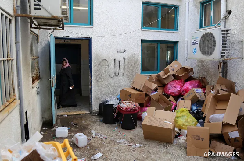 Palestinians stand near pile of waste during strike of Palestinian cleaners at al-Shifa hospital in Gaza City on February 13, 2018. Photo by Atia Darwish