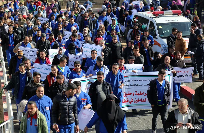 Palestinian cleaners hold banners during a protest to demand their salaries, at al-Shifa hospital in Gaza City on February 13, 2018. Photo by Atia Darwish
