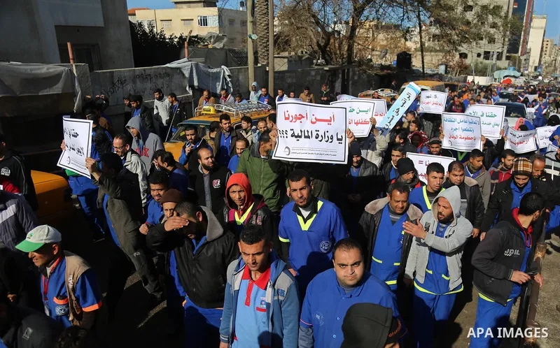 Palestinian cleaners hold banners during a protest to demand their salaries, at al-Shifa hospital in Gaza City on February 13, 2018. Photo by Atia Darwish