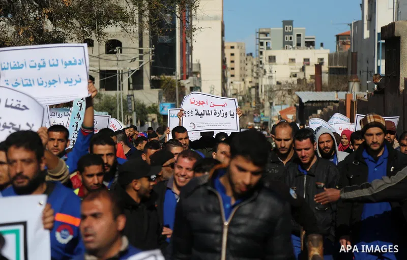 Palestinian cleaners hold banners during a protest to demand their salaries, at al-Shifa hospital in Gaza City on February 13, 2018. Photo by Atia Darwish