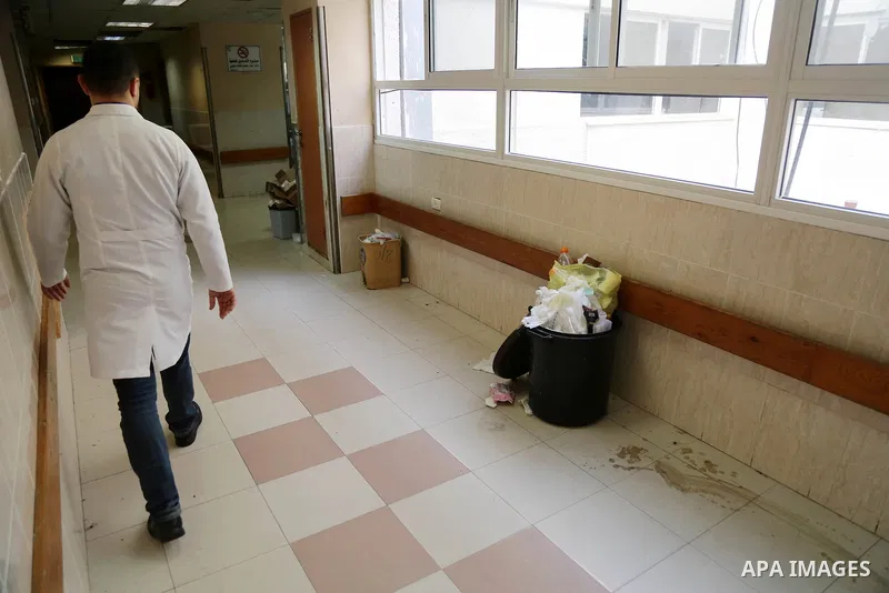 Palestinians stand near pile of waste during strike of Palestinian cleaners at al-Shifa hospital in Gaza City on February 13, 2018. Photo by Atia Darwish