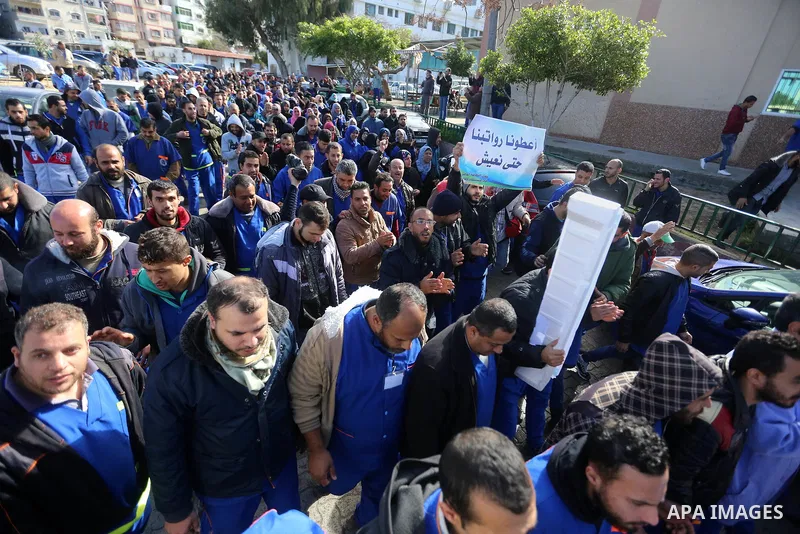 Palestinian cleaners hold banners during a protest to demand their salaries, at al-Shifa hospital in Gaza City on February 13, 2018. Photo by Atia Darwish