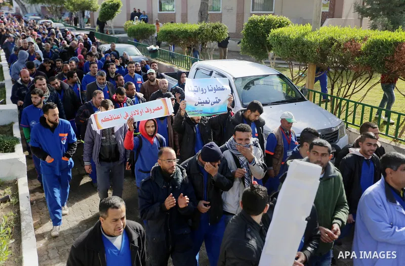 Palestinian cleaners hold banners during a protest to demand their salaries, at al-Shifa hospital in Gaza City on February 13, 2018. Photo by Atia Darwish