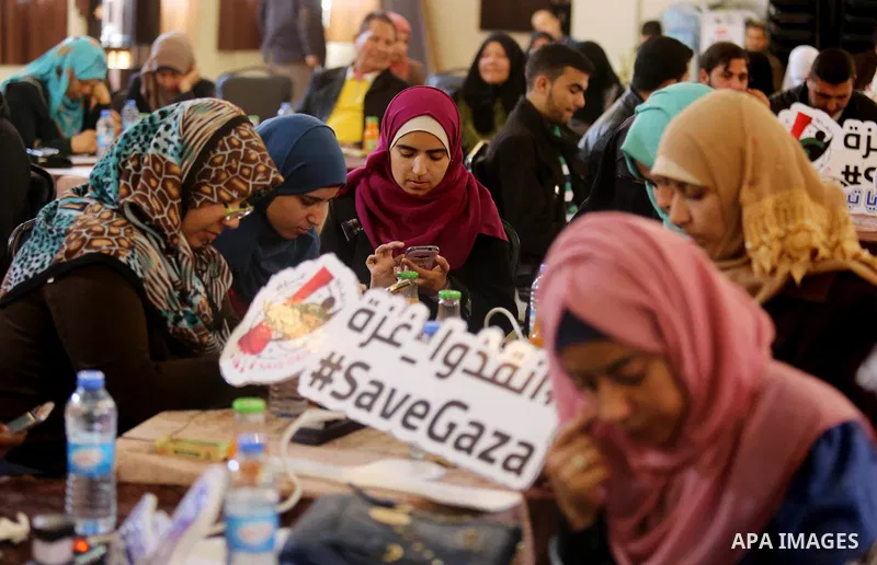 Palestinians tweet with the hashtag "#SaveGaza" against the siege on the Gaza Strip, in Gaza city, on February 14, 2018. Photo by Ashraf Amra