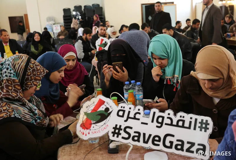 Palestinians tweet with the hashtag "#SaveGaza" against the siege on the Gaza Strip, in Gaza city, on February 14, 2018. Photo by Ashraf Amra