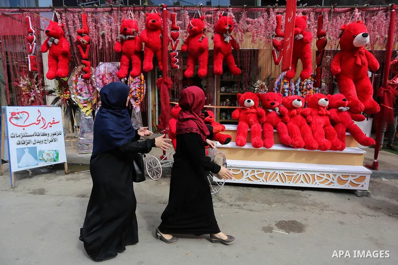 Palestinian women walk past a shop selling red teddy bears, red ballons and pillows on Valentine's day in Gaza city on February 14, 2018. Valentine's Day is increasingly popular in the region as people have taken up the...