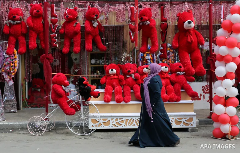 A Palestinian woman walks past a shop selling red teddy bears, red ballons and pillows on Valentine's day in Gaza city on February 14, 2018. Valentine's Day is increasingly popular in the region as people have taken up t...