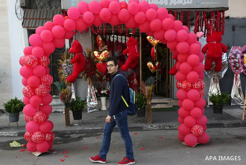 A Palestinian youth walks past a shop selling red teddy bears, red ballons and pillows on Valentine's day in Gaza city on February 14, 2018. Valentine's Day is increasingly popular in the region as people have taken up t...
