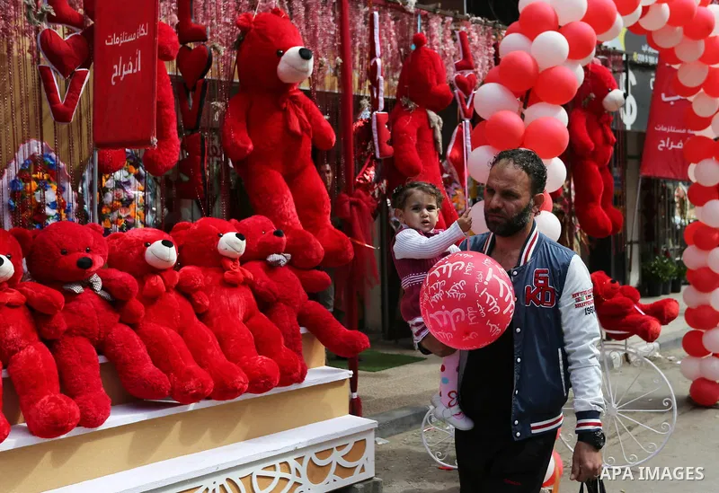 A Palestinian man walks past a shop selling red teddy bears, red ballons and pillows on Valentine's day in Gaza city on February 14, 2018. Valentine's Day is increasingly popular in the region as people have taken up the...